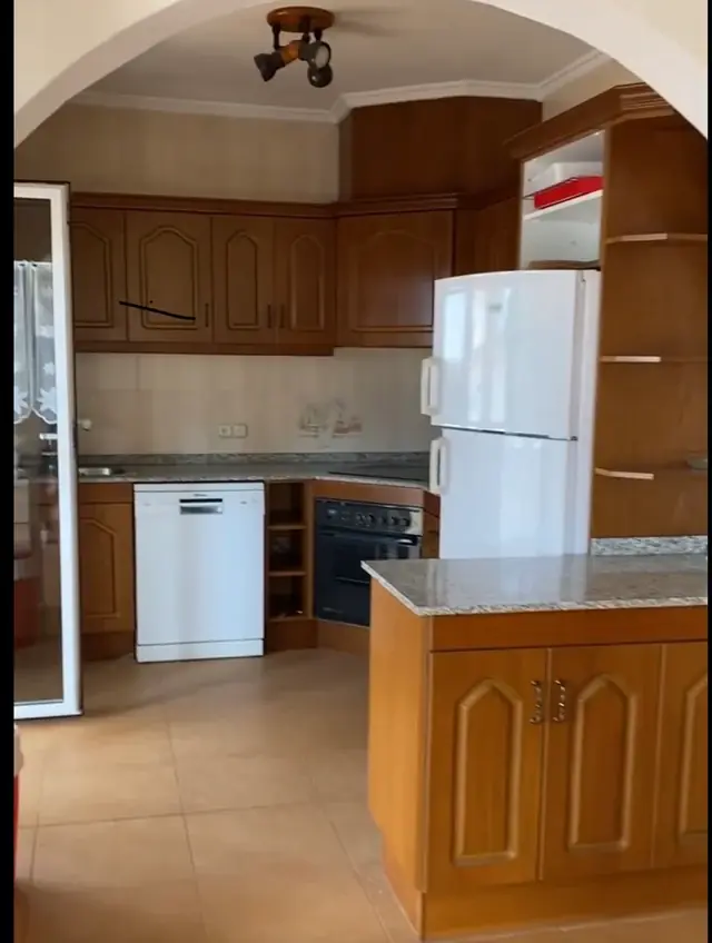 Keuken vóór de renovatie met houten kastfronten, granieten werkblad en witte koelkast